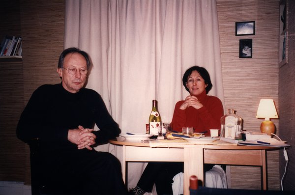 Un homme et une femme assis à une table ronde avec une bouteille de vin.ᴬᴵ