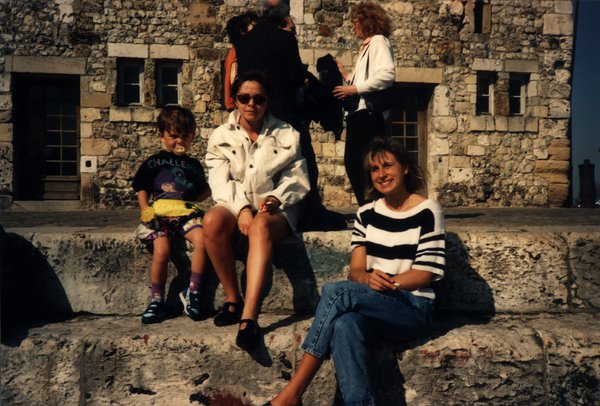 Femme, enfant et une autre femme assis sur un rempart de pierre.ᴬᴵ