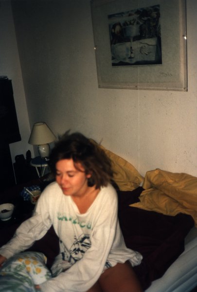 Femme assise sur un lit en chemise de nuit, cheveux ébouriffés.ᴬᴵ