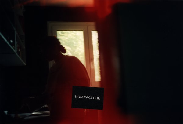 Silhouette d'une personne devant une fenêtre, photo surexposée aux tons rouges.ᴬᴵ
