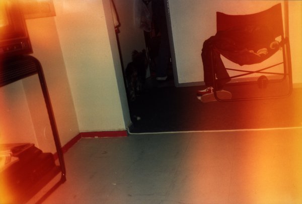 Coin de pièce avec chaise pliante et silhouette dans l'embrasure, photo avec halo de lumière orangé.ᴬᴵ