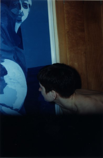 Visage de femme brune tournée vers une grande peinture bleue.