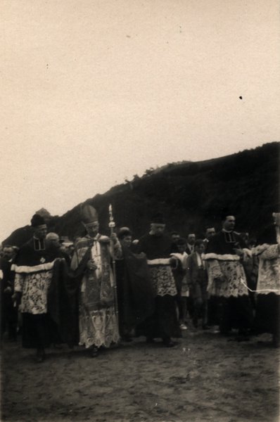 Évêque en mitre et clergé en procession sur une plage. Photo ancienne sépia.ᴬᴵ