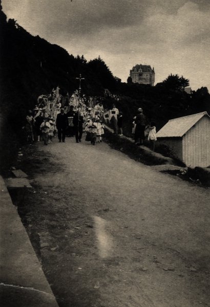 Procession sur un chemin avec château visible au loin sur la colline. Photo ancienne sépia.ᴬᴵ