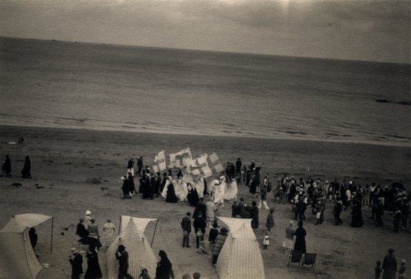 Procession avec bannières sur une plage face à la mer. Photo ancienne sépia.ᴬᴵ