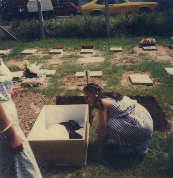Femme accroupie devant un cercueil dans un cimetière pour animaux.