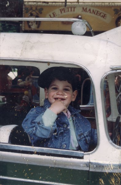 Un petit enfant brun assis dans une voiture de manège.