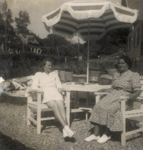 Deux femmes en tennis blanches assises  sous un parasol dans un jardin. Noir et blanc.
