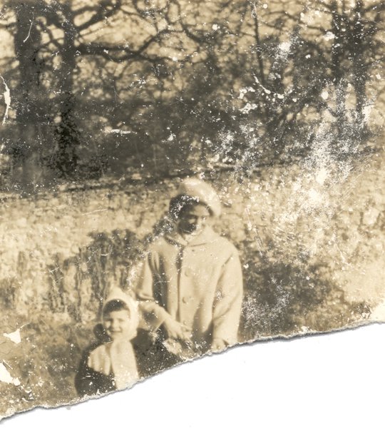 Femme en manteau avec un enfant dans un jardin. Noir et blanc. Image déchirée.