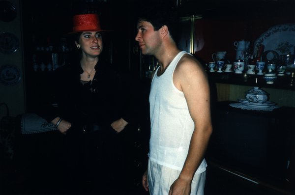 Femme au chapeau rouge et homme en débardeur blanc devant une vaisselle décorative.ᴬᴵ