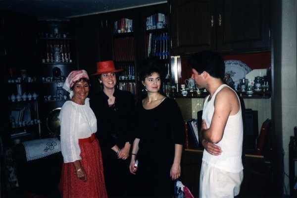 Groupe de quatre personnes devant une bibliothèque et une vaisselle décorative lors d'une soirée.ᴬᴵ