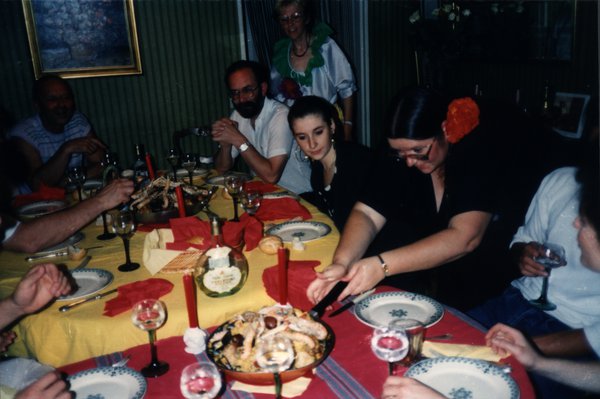 Repas de groupe autour d'une table dressée, plat servi au centre.ᴬᴵ
