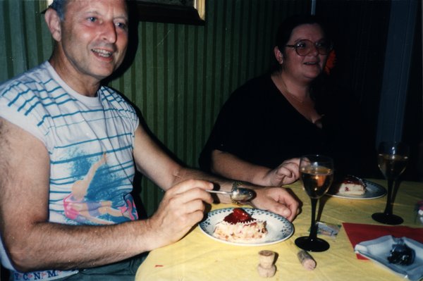 Homme âgé mangeant un gâteau à table, une femme à ses côtés.ᴬᴵ