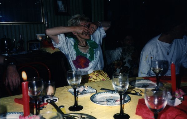 Femme se couvrant le visage des mains à une table de dîner avec bougies.ᴬᴵ