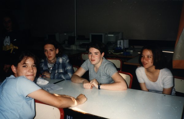 Quatre adolescentes assises à une table dans une salle informatique.ᴬᴵ