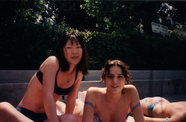 Deux jeunes femmes assises au bord d'une piscine en maillot de bain.ᴬᴵ