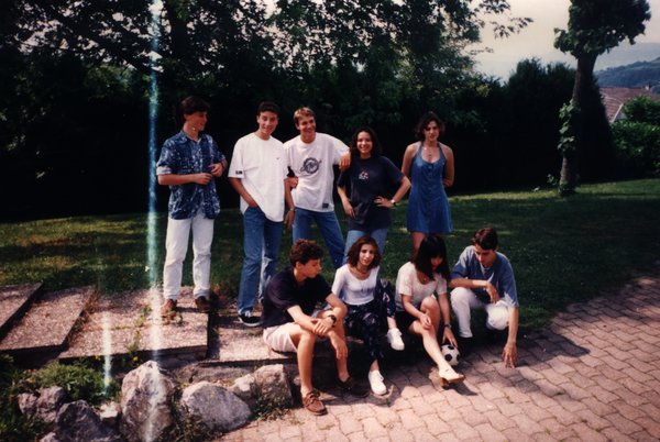 Groupe d'adolescents posant sur des marches en pierre à l'extérieur.ᴬᴵ