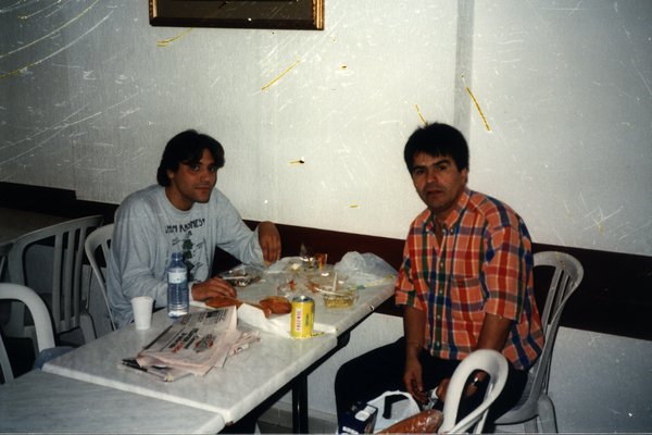 Deux hommes attablés dans un restaurant avec de la nourriture et des boissons.ᴬᴵ