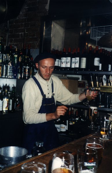 Barman servant une boisson derrière un comptoir de bar.ᴬᴵ