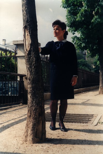 Femme en tenue marine appuyée contre un arbre dans un parc.ᴬᴵ