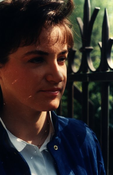 Portrait rapproché d'une femme en veste bleue près d'une grille.ᴬᴵ