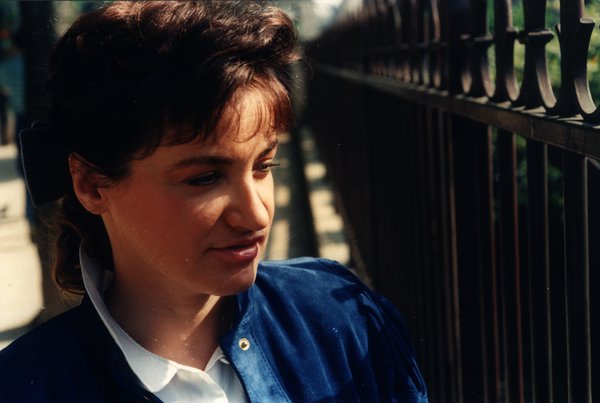 Portrait rapproché d'une femme en veste bleue souriant légèrement.ᴬᴵ