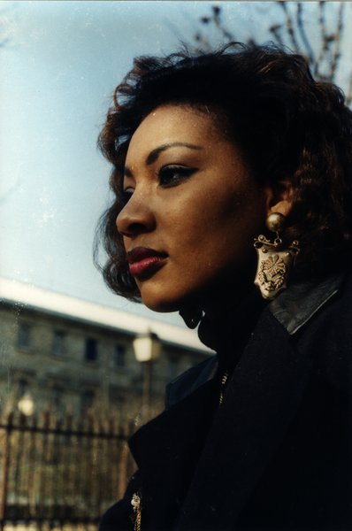 Portrait de profil d'une femme aux cheveux bouclés près d'une grille en fer forgé.ᴬᴵ