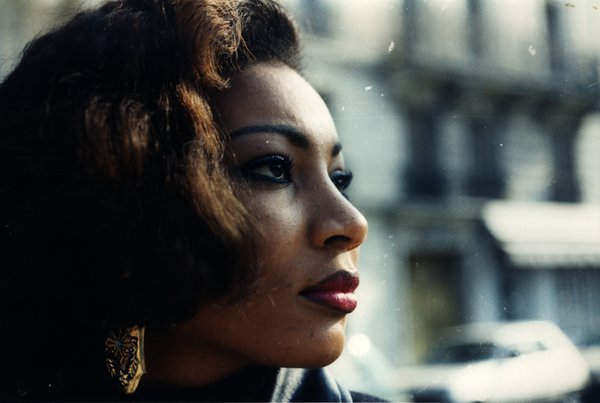 Portrait de profil d'une femme aux cheveux bouclés portant une boucle d'oreille ornée.ᴬᴵ