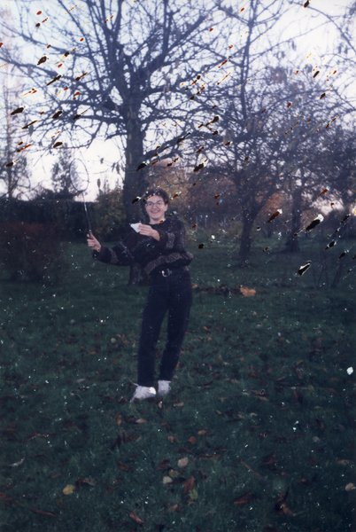 Femme dans un jardin avec une raquette de badminton et un volant dans la main.