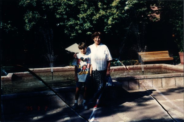 Femme et enfant devant une fontaine dans un parc.ᴬᴵ