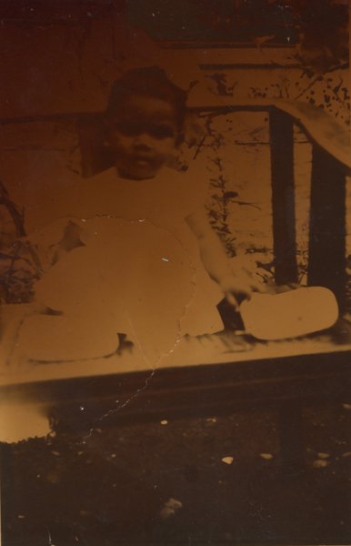 Enfant en barboteuse assis sur un fauteuil.