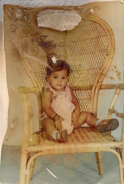 Petite fille assise dans un fauteuil en osier.