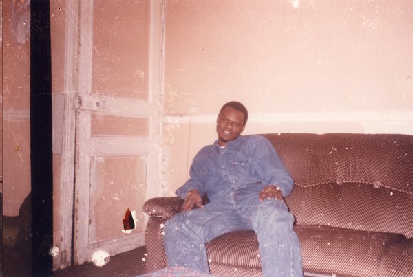 Homme souriant assis sur un canapé brun.