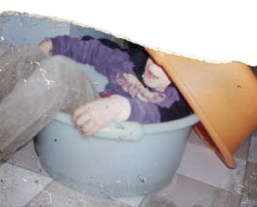 Enfant caché dans deux bassines plastiques. Fragment.