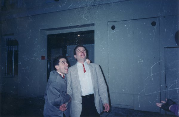 Deux hommes bouches ouvertes regardent en l’air et se prennent par les épaules.