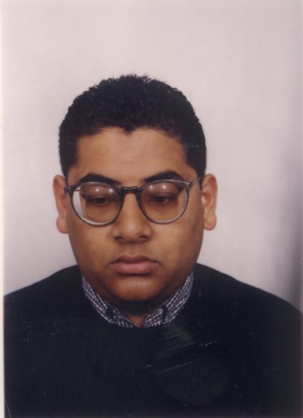 Visage d’homme brun à lunettes.
