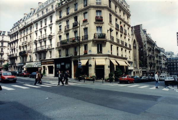 Carrefour à Paris avec passants et voitures.