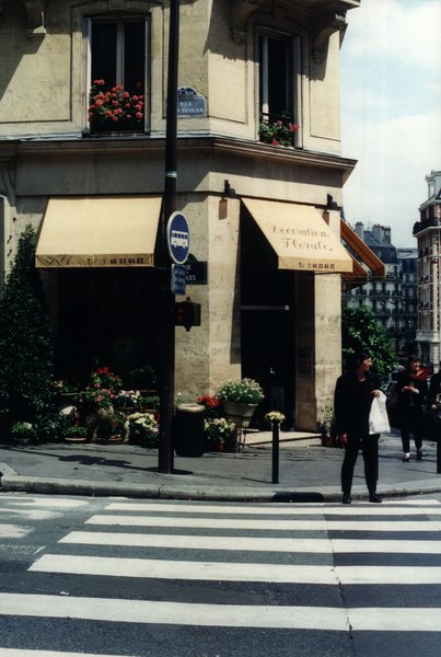 Magasin de fleurs au coin d’une rue parisienne et passage piéton.
