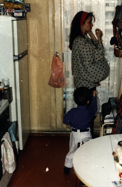 Femme enceinte en robe à pois dans une cuisine avec un jeune garçon.ᴬᴵ