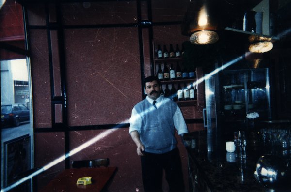 Homme derrière un comptoir de bar avec des bouteilles.ᴬᴵ
