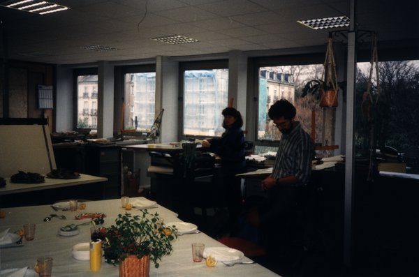 Bureau aménagé pour un repas avec deux personnes en arrière-plan.ᴬᴵ