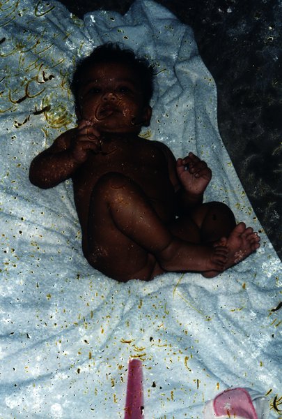 Bébé nu allongé sur un tissu. Image avec taches.ᴬᴵ