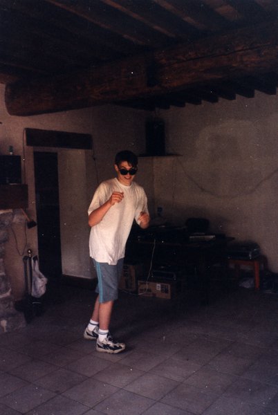 Jeune homme dansant avec des lunettes de soleil, poutres apparentes au plafond.ᴬᴵ