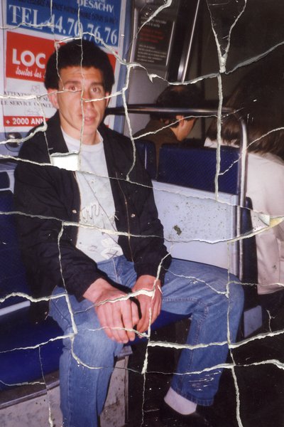 Homme brun assis dans les transports. Image déchirée en partie reconstituée.