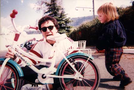 Homme brun avec un petit enfant blond et un vélo d’enfant.