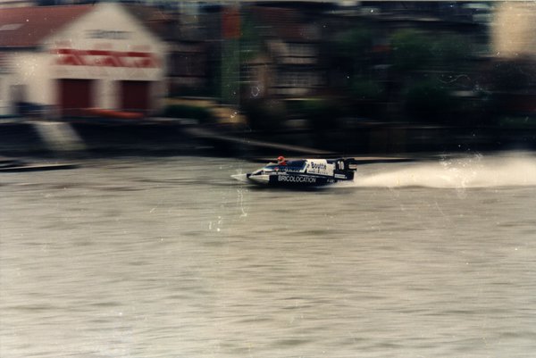 Bateau de course devant des maisons au bord de l'eau.ᴬᴵ