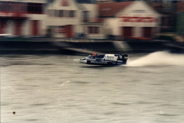 Bateau de course devant des maisons au bord de l'eau.ᴬᴵ