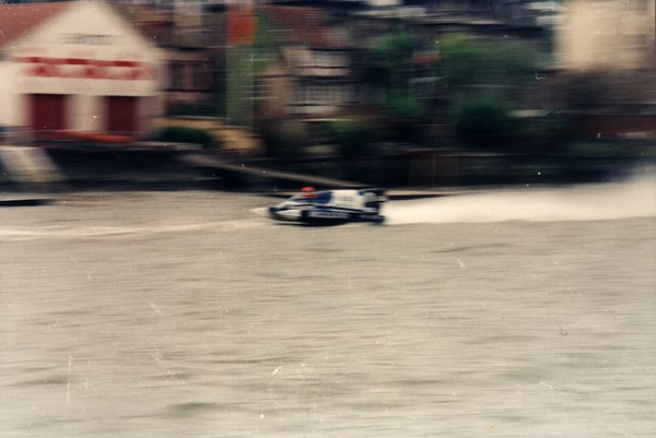 Bateau de course devant des maisons au bord de l'eau.ᴬᴵ