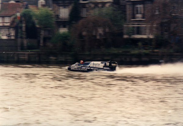Bateau de course Boutté devant des maisons de ville au bord de l'eau.ᴬᴵ
