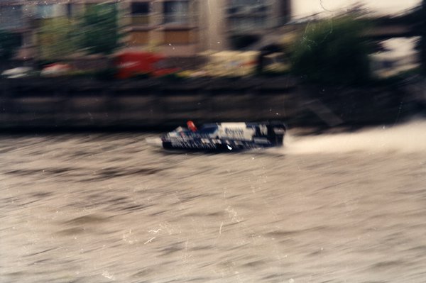 Bateau de course Boutté devant des immeubles aux auvents colorés.ᴬᴵ